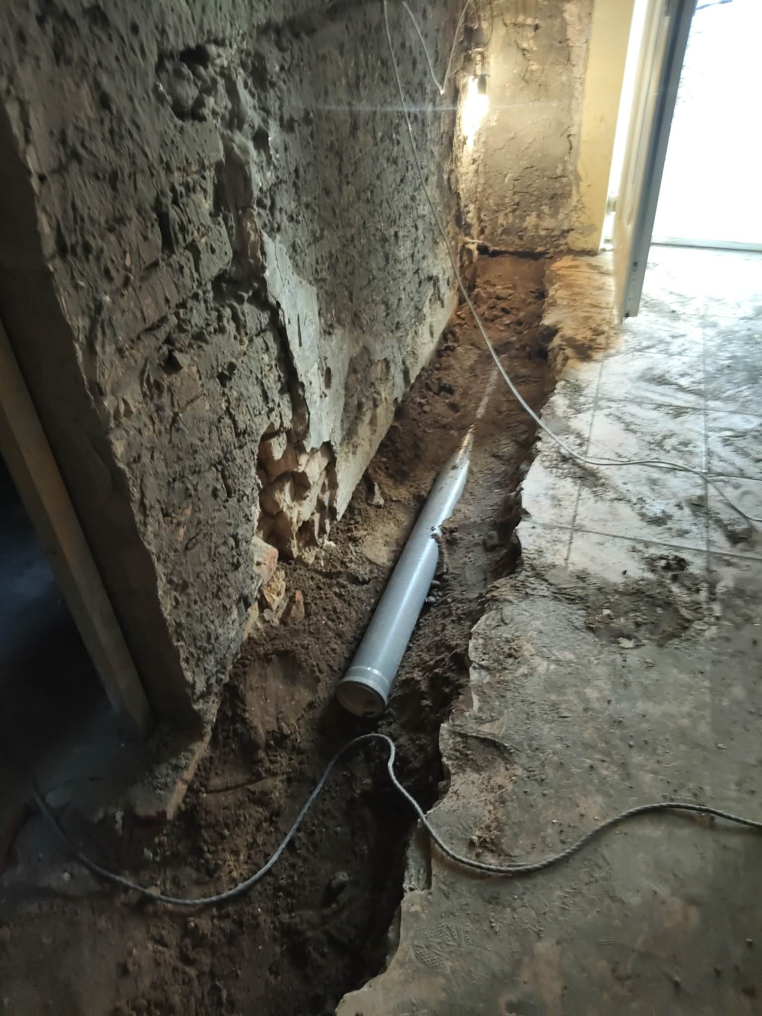 Fal mellett kivésett nyomvonal és gépészeti cső egy 70 m²-es házrész felújításánál